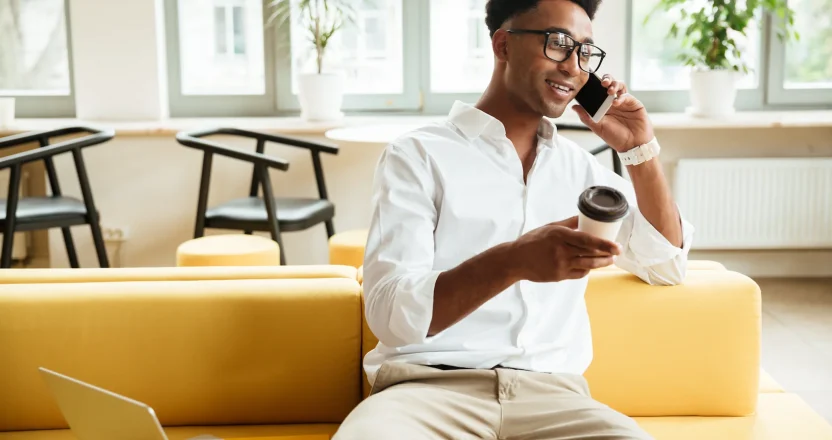 A property manager in Nebraska talking to a tenant while sitting on a yellow sofa.