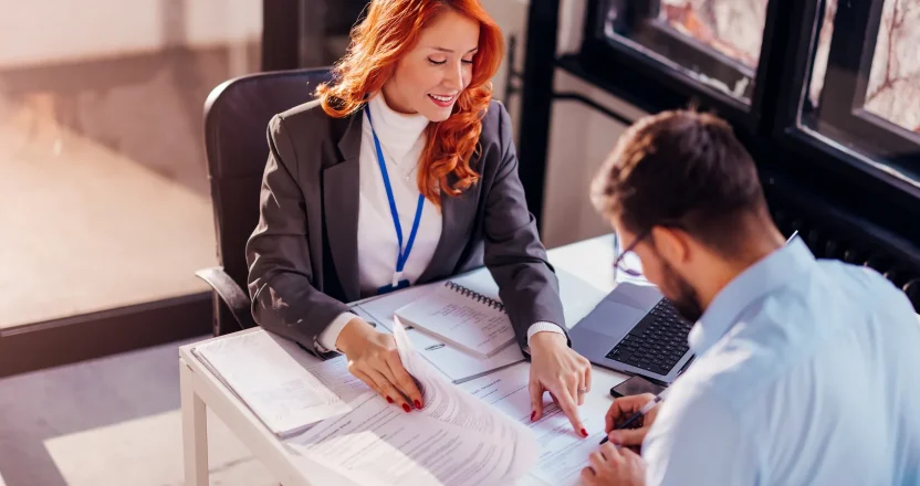 A property manager in oregon having her tenant sign rental papers in an office.